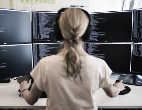 Sakerhetsbolagets-SRS-it-specialist-sitter-framfar-stor-datorskarm-och-arbetar-med-cybersakerhet